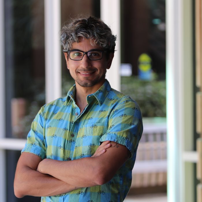 Kenny Easwaran in 2023, in a bicycle-print shirt, outside a building on campus